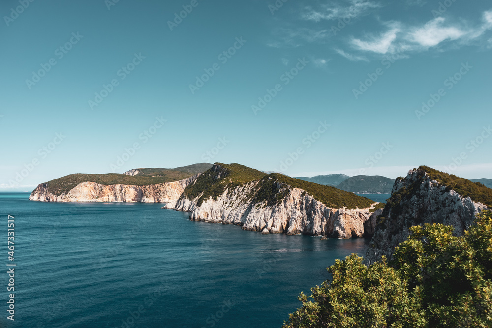 Panoramic view on vivid blue sea and steep green cliffs, sunny sea shore on a bright clear day in Greece. Scenic travel. Lefkada island, Ionian sea coast. Color graded