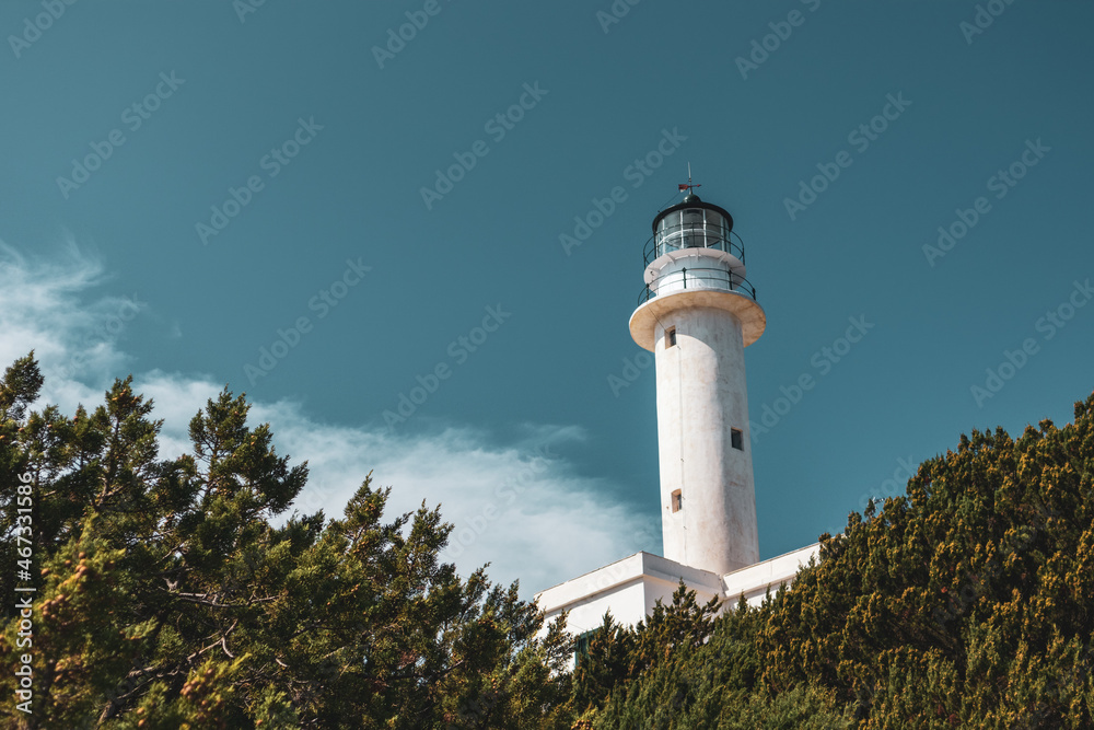 White lighthouse tall tower in greenery on a bright clear blue sky in Greece, Ionian sea. Scenic travel destination. Lefkada island. Color graded White lighthouse tall tower in greenery on a bright clear blue sky in Greece, Ionian sea. Scenic travel destination. Lefkada island. Color graded