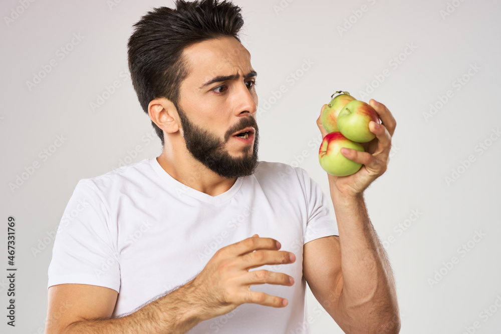Cheerful man with apples in his hands in a white t-shirt fruits Cheerful man with apples in his hands in a white t-shirt fruits