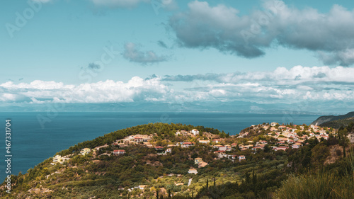 Color graded panoramic traditional greek village with orange tiled roofs on green hills near blue sea shore on Lefkada island, Greece. Travel Europe in summer