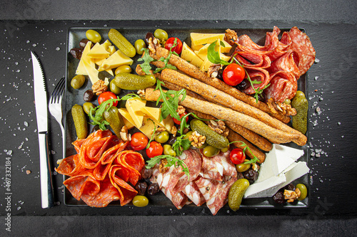 Charcuterie Board with Various Pickles, Cheeses, and Meats - Cucumbers, Olives, Cheese Cubes, Pepperoni and Bread Sticks photo