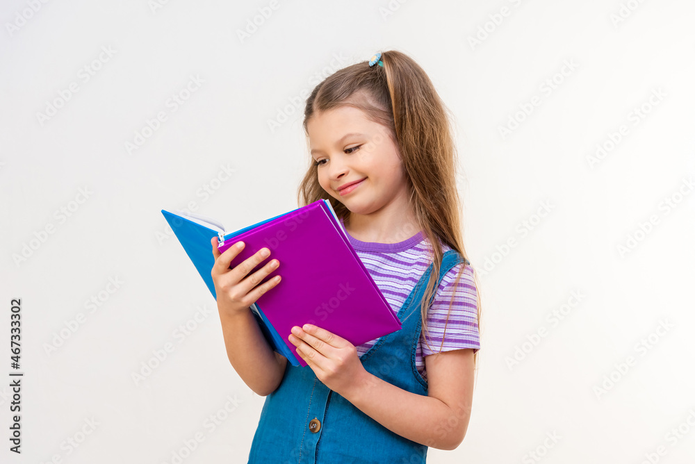 A schoolgirl reads an interesting story in a book on a white background. A schoolgirl reads an interesting story in a book on a white background.