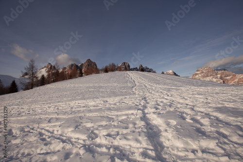 Snowy slope with human traces, with a beautiful backdrop of Rocchette and Sorapiss Dolomite peaks at sunset. San Vito di Cadore, Dolomites, Italy