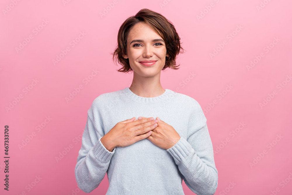 Photo of positive nice young happy woman hold hand heart smile enjoy nice isolated on pink color background Photo of positive nice young happy woman hold hand heart smile enjoy nice isolated on pink color background