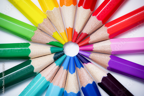 Color wheel or color theory concept with colored pencils. Colored crayons arranged in a circle against a white background. Table top view, flat lay.
