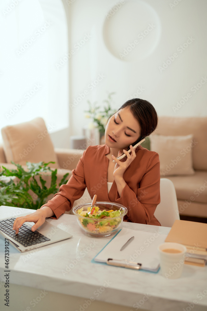 Pretty woman smiling while working from home, on the phone with a salad Pretty woman smiling while working from home, on the phone with a salad