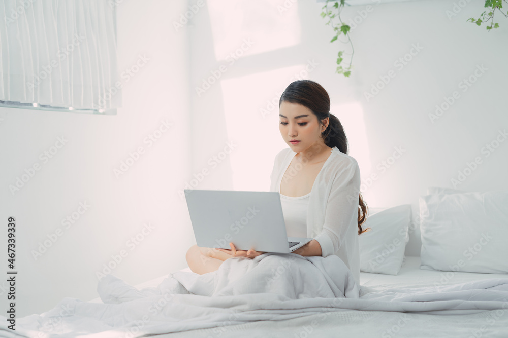 Young woman using laptop computer on a cold winter day in the bedroom. Young woman using laptop computer on a cold winter day in the bedroom.