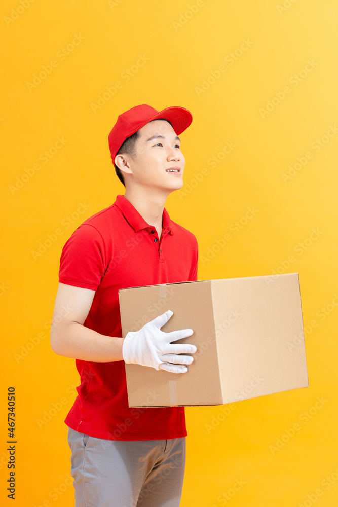 Handsome young delivery man with box isolated on yellow background. Handsome young delivery man with box isolated on yellow background.
