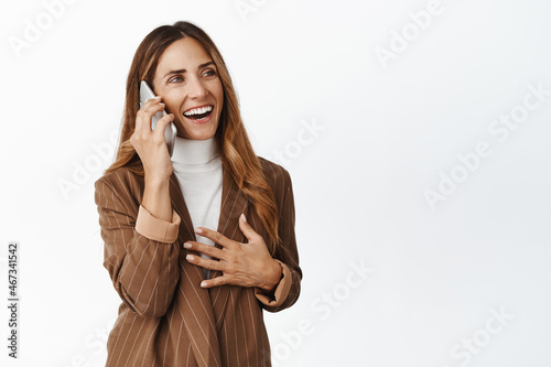 Fototapeta Successful corporate woman 40s talking on mobile phone, laughing on call, concep