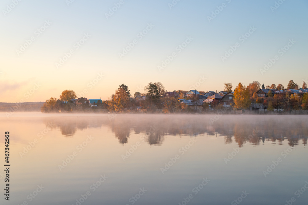 Fototapeta premium Village in autumn on the shore of a pond in the morning
