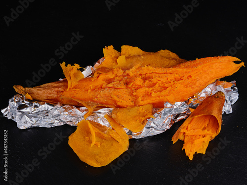 Sweet potato baked on dark stone. Rumpled aluminum foil
