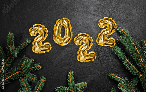 Creative Christmas background with green fir branches and 2022 text golden foil balloons decor. Flat lay, top view