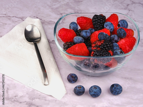 Berries on bowl. Metal spoon. Marble background