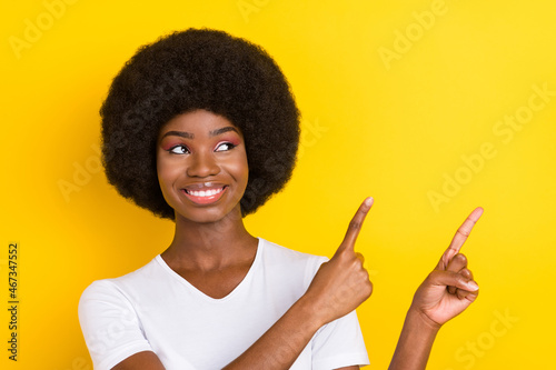 Photo of attractive nice dark skin young woman point fingers look empty space isolated on yellow color background