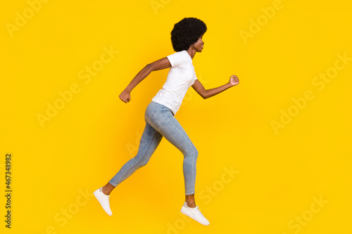 Full length photo of sweet charming dark skin lady wear white t-shirt jumping high running fast isolated yellow color background