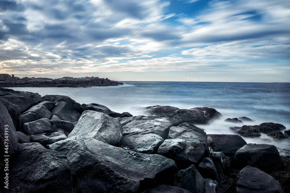 Obraz premium Dramatic seascape with stones on the shore. Long exposure. Blurred water. Coast of the Atlantic Ocean. USA. Maine.