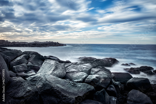 Dramatic seascape with stones on the shore. Long exposure. Blurred water. Coast of the Atlantic Ocean. USA. Maine.