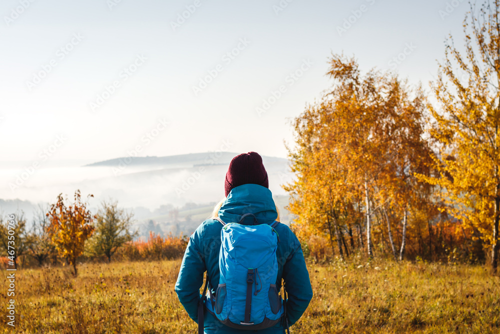 Enjoyment of autumn hike in nature. Woman tourist with backpack and knit hat looking at beautiful scenery. Hiking outdoors in fall season Enjoyment of autumn hike in nature. Woman tourist with backpack and knit hat looking at beautiful scenery. Hiking outdoors in fall season