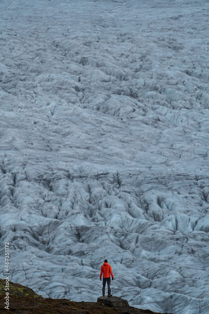 Spectacular rear view of unrecognizable tourist against glacier