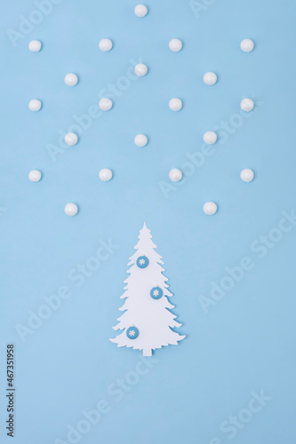Christmas creative concept. White Christmas tree of paper with snow on the blue background. Holiday concept.