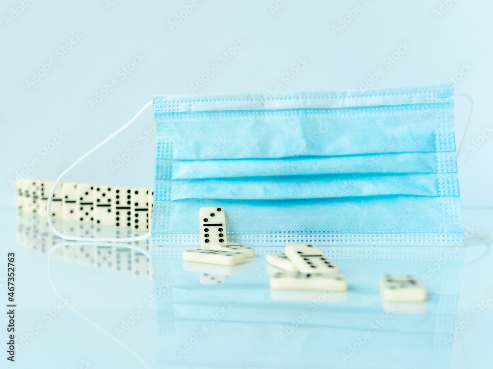 Surgical mask stopping domino effect falling. Covid-19 concept. Surgical mask stopping domino effect falling. Covid-19 concept.