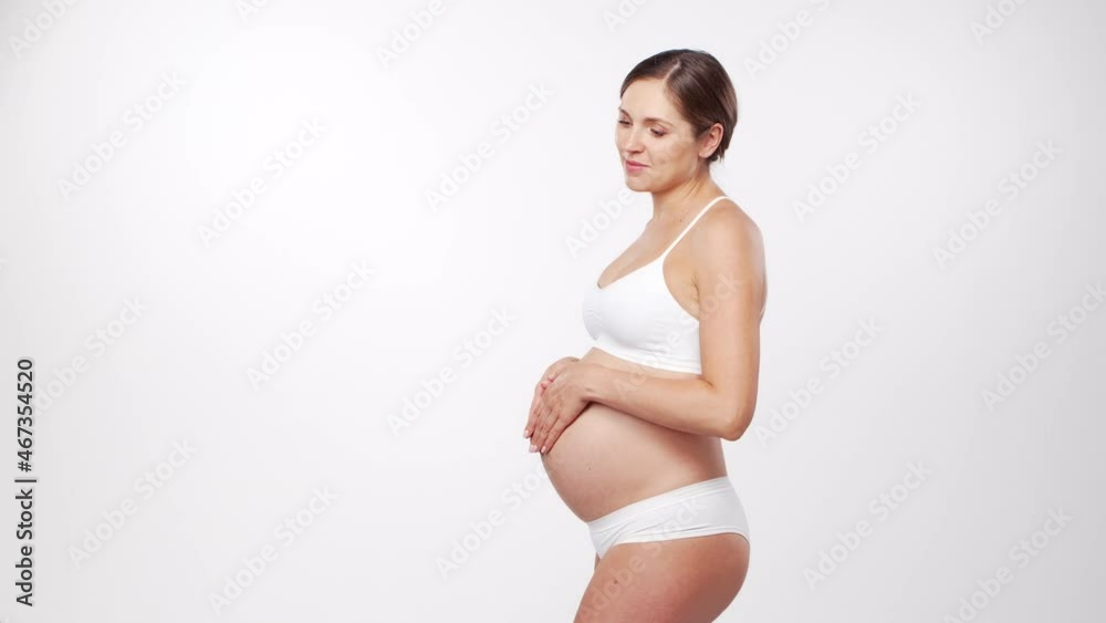 Young, happy and healthy pregnant woman on white background. Studio video. Baby expectation, pregnancy and motherhood concept.