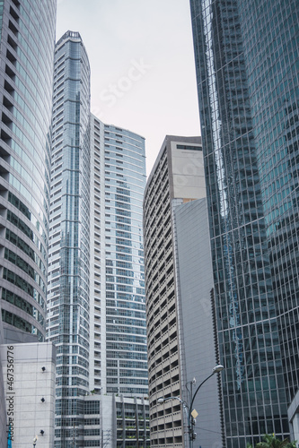 Vertical photograph of Makati city skyscrapers reflecting each other on a cloudy day. Urban photography © Sin Filtro