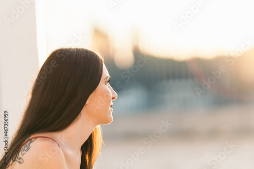 Profile of a young woman gazing the horizon during sunset from a park