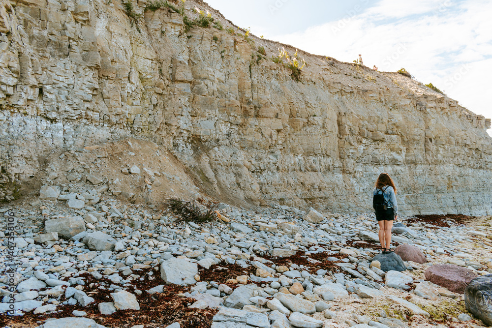 Woman with brown curly hair hiking by the Panga cliff in Saaremaa, Estonia during sunny day. The highest bedrock outcrop in western Estonia on coast of the Baltic sea Woman with brown curly hair hiking by the Panga cliff in Saaremaa, Estonia during sunny day. The highest bedrock outcrop in western Estonia on coast of the Baltic sea