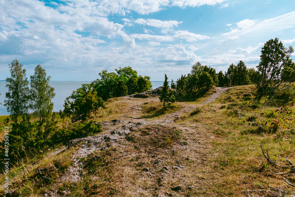 Uugu bluff or cliff on the Muhu Island in Estonia, located by the Baltic sea and near the island of Saaremaa. Beautiful sunny day with blue sky, white clouds, forest and stone cliffs by the seaside. Uugu bluff or cliff on the Muhu Island in Estonia, located by the Baltic sea and near the island of Saaremaa. Beautiful sunny day with blue sky, white clouds, forest and stone cliffs by the seaside.