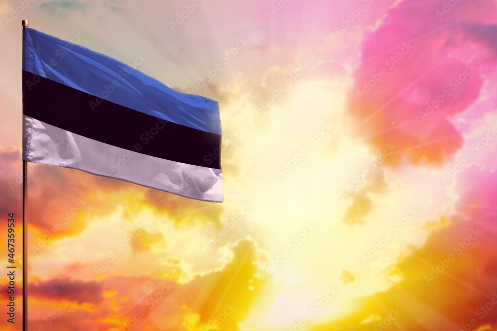 Fluttering Estonia flag in top left corner mockup with the space for your text on beautiful colorful sunset or sunrise background.