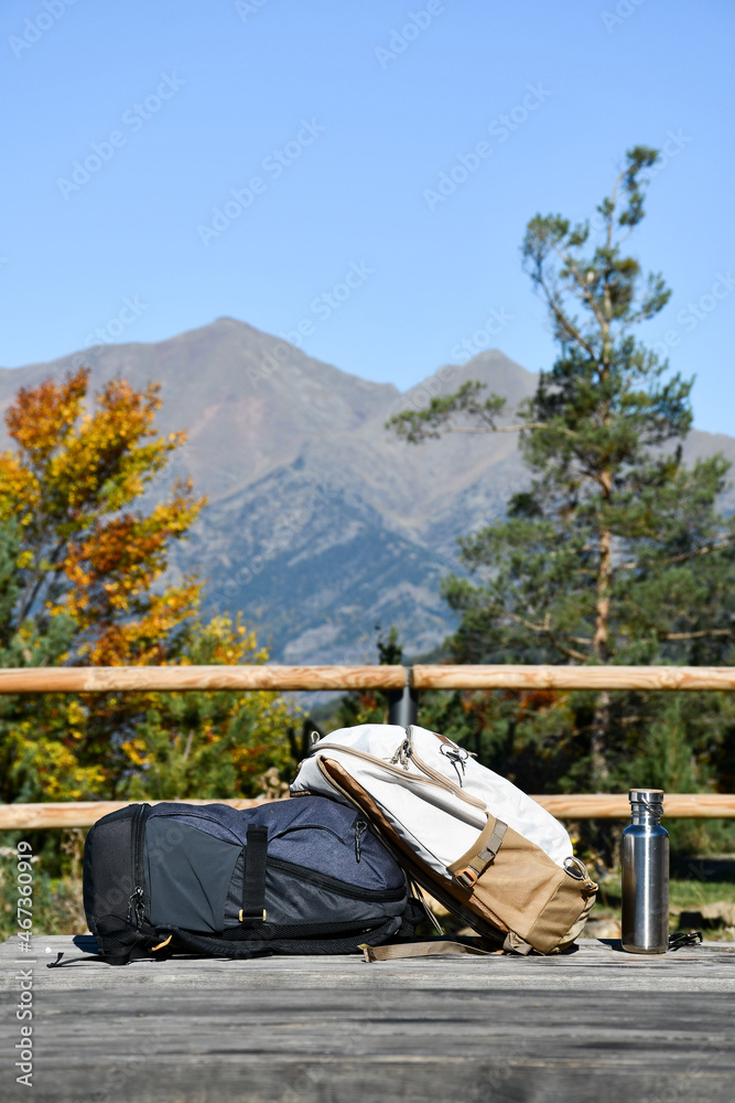 Two backpacks and a metal water bottle a picnic table with mountain views