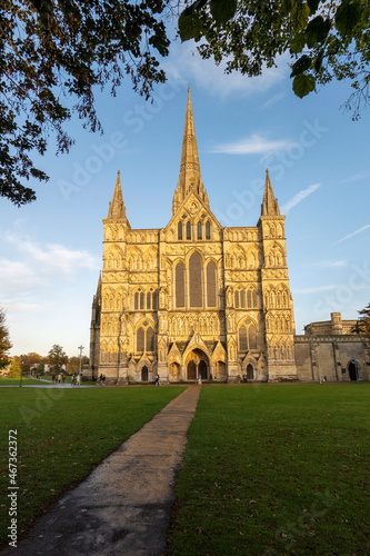 Salisbury, Wiltshire, England, UK. 2021. Salisbury Cathedral, west front seen with glow of the setting sun and a blue sky.