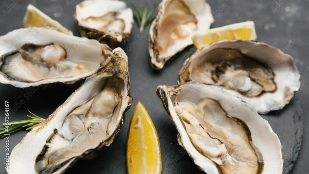 Closeup view of raw oysters with lemon on black platter