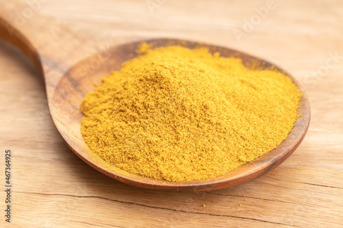 Curry powder in wooden spoon on wooden table. Close up