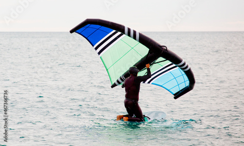 Man practicing wing foil with hydrofoil at sunset in the sea. © Fernando