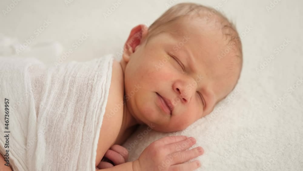 Closeup portrait of adorable newborn baby sleeping. Swaddled infant child in white fabric napping. Beautiful kid resting Closeup portrait of adorable newborn baby sleeping. Swaddled infant child in white fabric napping. Beautiful kid resting