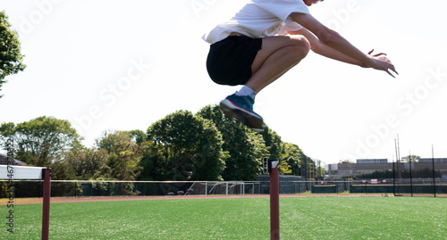 Athlete jujnping over track hurdles