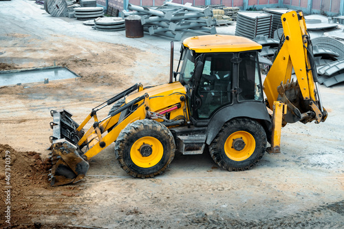 A multipurpose excavator with a front bucket transports soil to the construction site. View from above. Construction machinery for earthworks.