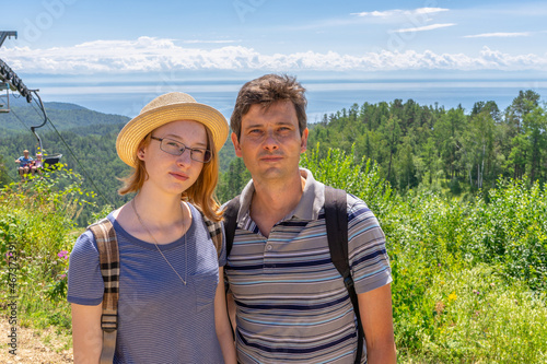 Tourists handsome middle aged man and attractive teen girl posing against beautiful landscape in sunny summer day. Father and daughter looking at camera. Travel, summer vacation. Siberia, Russia © Tatyana_Andreyeva