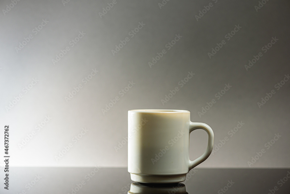 Black coffee in a white ceramic cup on a gray background a place for an inscription. Side view, top view. Selective focus Black coffee in a white ceramic cup on a gray background a place for an inscription. Side view, top view. Selective focus