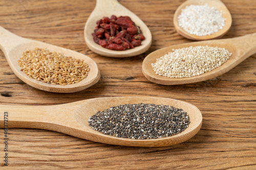 Assorted superfoods in spoons over wooden table. Chia, quinoa, oat, linseed and goji berry