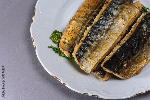 Wallpaper Mural Fried mackerel with a short body file or Platoo in Thai is served on a white porcelain plate on a gray background. Popular fish menu in Thailand. (close-up, side view)  Torontodigital.ca