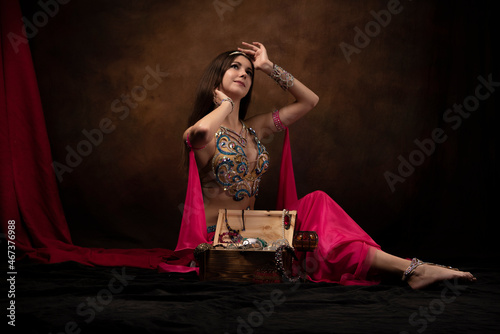 A girl in the image of an oriental princess is sitting next to a treasure chest. Oriental fairy tale, belly dance, Scheherazade.