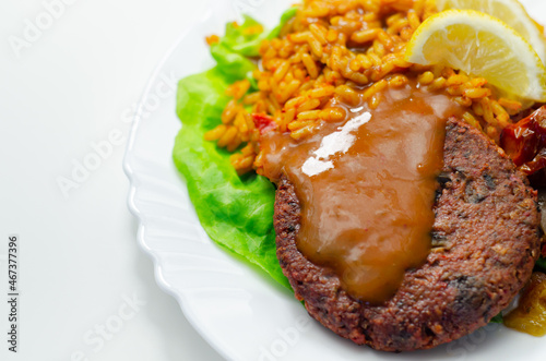 Meat free burger and long grain rice with red peppers, tomatoes and jalapeno chillies