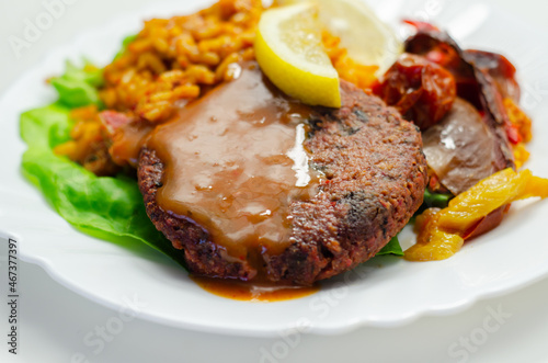 Meat free burger and long grain rice with red peppers, tomatoes and jalapeno chillies photo