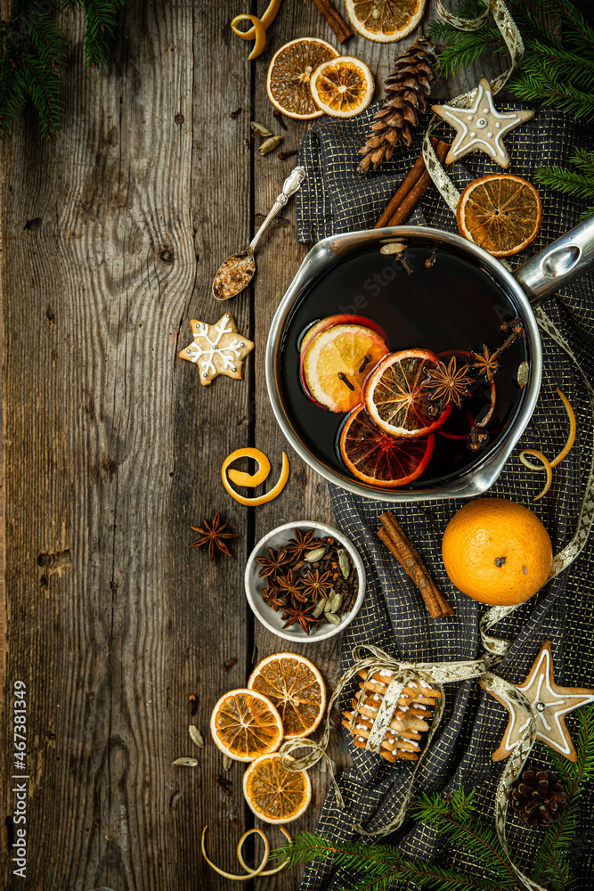 Top view ingredients for Swedish glögg on wooden background. Traditional Nordic drink. Mulled wine with spices, orange and raisins.