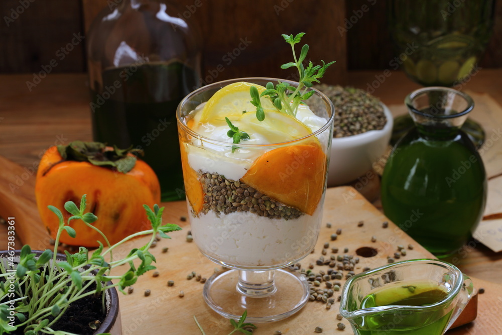 Dessert with yogurt, persimmon and hemp sativa sprouts on wooden background