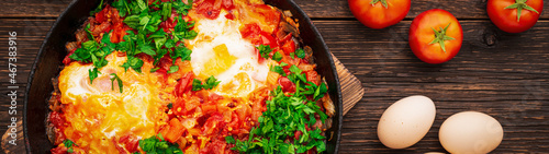 Cooked shakshuka in a frying pan on a wooden rustic background banner panoramic photo