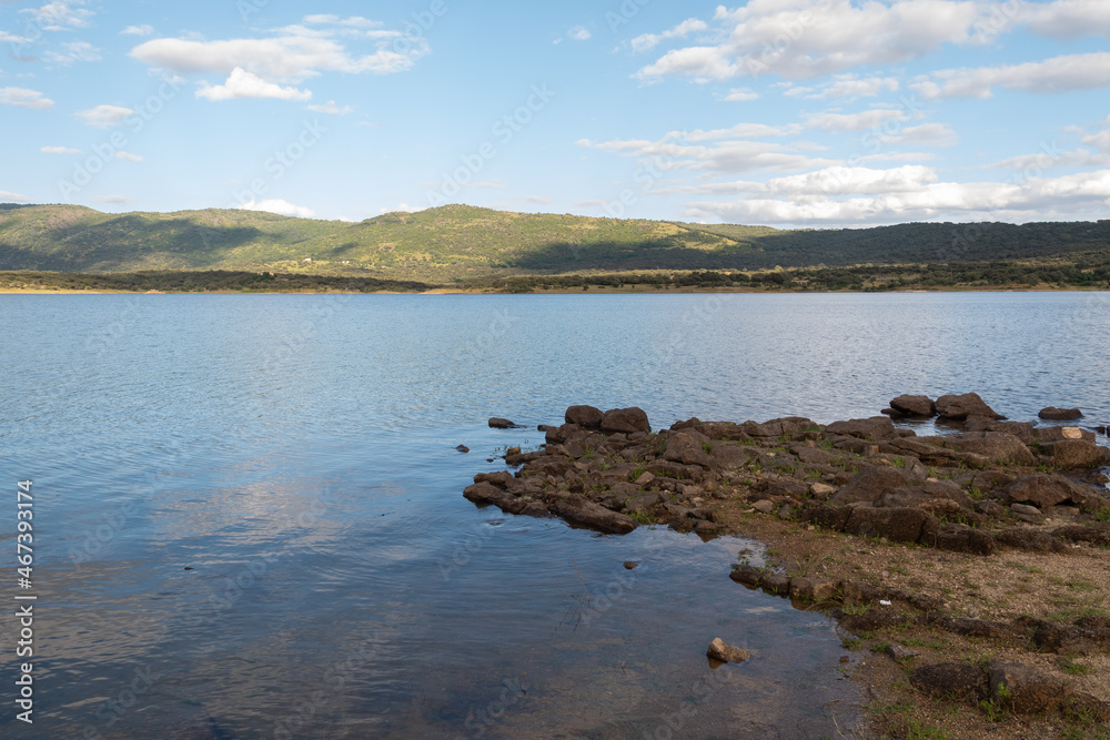 Landscape of a lake with a close-up of granite rocks piled up on the shore Landscape of a lake with a close-up of granite rocks piled up on the shore